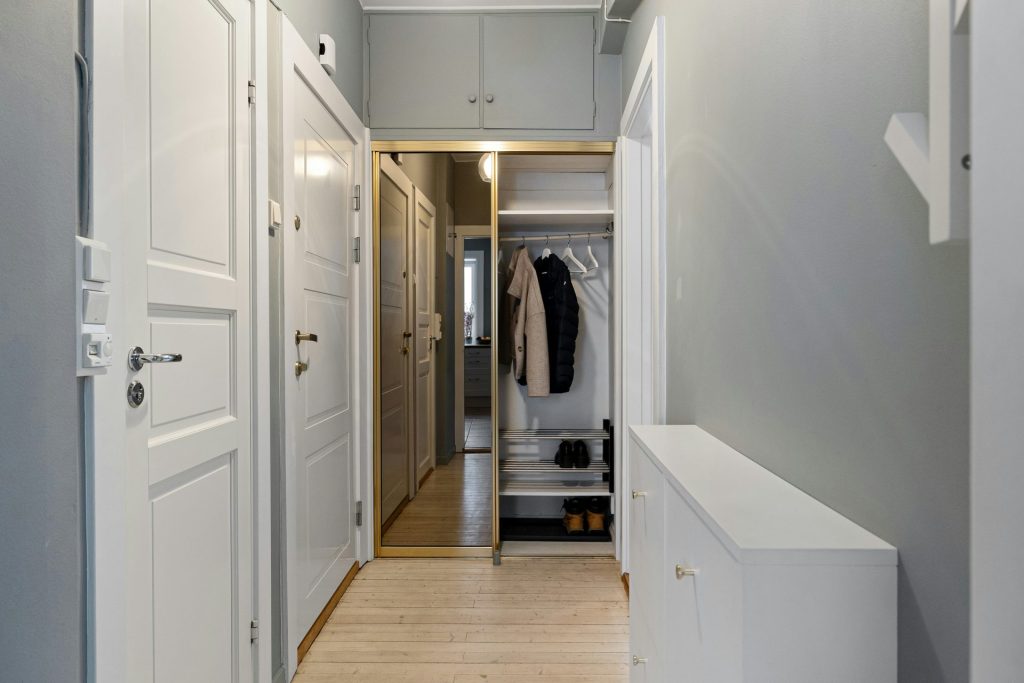 A narrow hallway with white doors leading to a closet